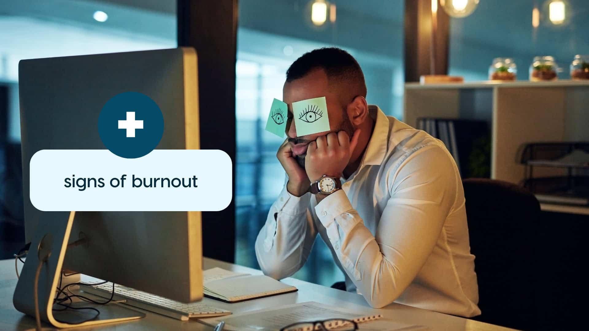 Man overwhelmed at work with signs of burnout on screen.