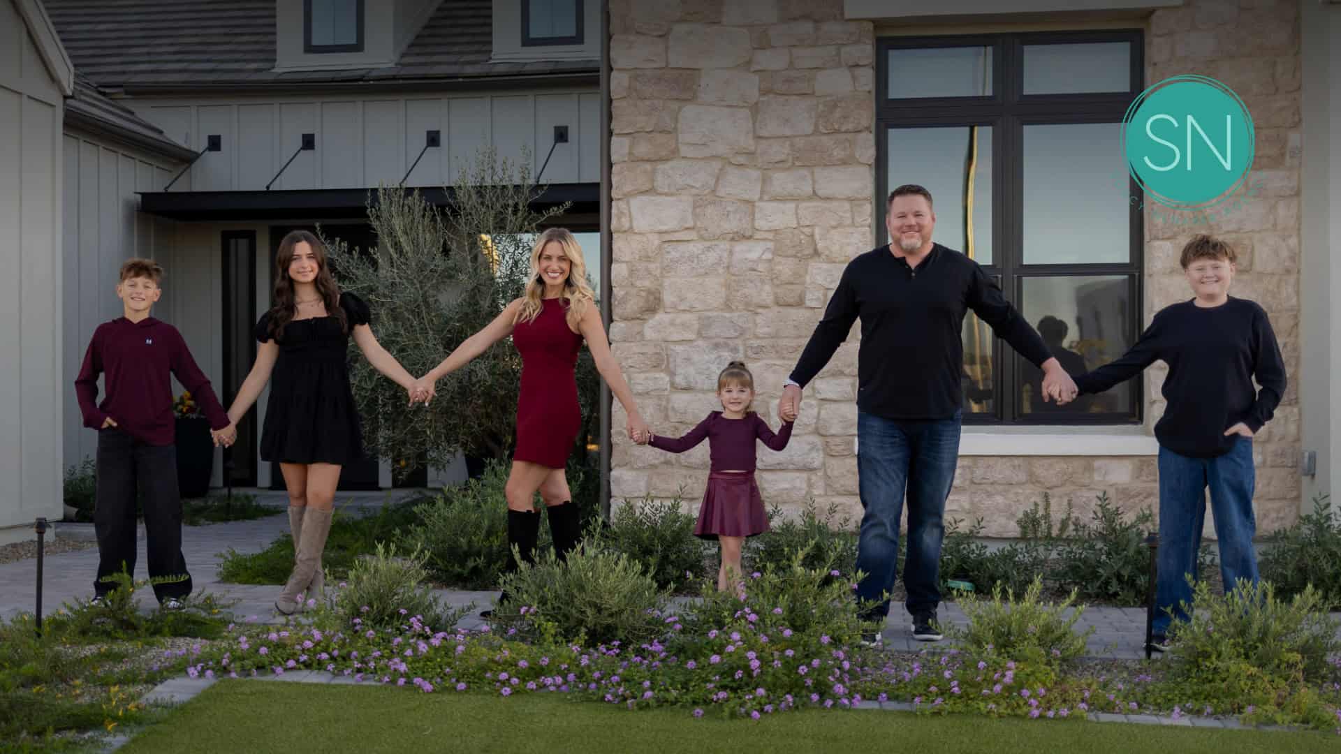 Happy family holding hands outside a modern house.